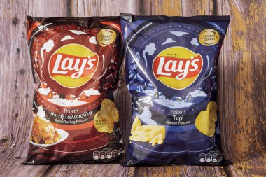 Thessaloniki, Greece - November 23 2024: Two Lay's chips bags with limited edition seasonal flavors, Roast Turkey and Cheese, photographed against a wooden rustic background. clipart