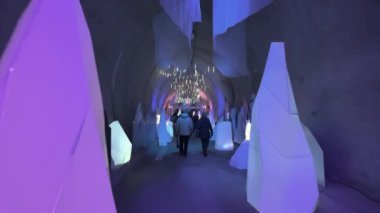 Zagreb, Hırvatistan - 15 Aralık 2024: Çevredeki mavi ışıklandırma altında buz oluşumlarını andıran aydınlatılmış geometrik yapıların yer aldığı Noel süslenmiş Gric tünel iç mimarisi.