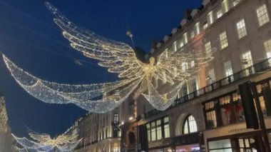 Londra, İngiltere - 27 Kasım 2024: Trafiğin ve yayaların yer aldığı festival süslemeleri ve sokak manzaralarıyla süslenmiş bir alışveriş merkezinde aydınlatılmış Noel Regent Caddesi.