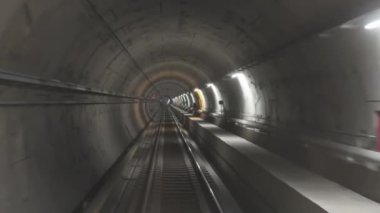 Sürücüsüz metro treni beton duvarlar ve rayların olduğu iyi aydınlatılmış bir yeraltı tünelinden geçiyor. Tünel düz ve uzunluğu boyunca Selanik, Yunanistan 'da parlak ışıklarla kaplı.