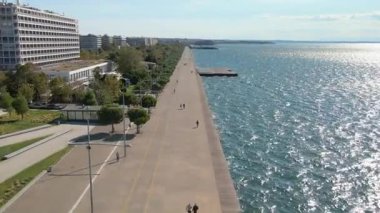 Selanik, Yunanistan - 30 Eylül 2020: Yürüyen kalabalığın bulunduğu Thermaic Gulf sahil şeridinin yanındaki Makedonia Palace Oteli ile birlikte şehrin sahil kesiminde alçak uçuş.