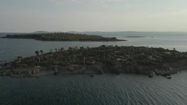 Yunanistan 'ın Chalkidiki yarımadasındaki Akdeniz' de yeşil bitki örtüsü ve kayalık kıyı şeritlerinin üzerinde gün uçuyor.