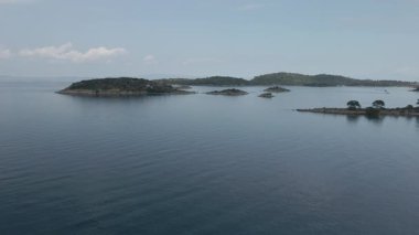 Yunanistan 'ın Chalkidiki yarımadasındaki Akdeniz' de yeşil bitki örtüsü ve kayalık kıyı şeritlerinin üzerinde gün uçuyor.