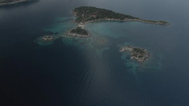 Yunanistan 'ın Chalkidiki yarımadasındaki Akdeniz' de ev, yeşil bitki örtüsü ve kayalık kıyı şeridi ile küçük ada şeridinin üzerinde uçma günü.