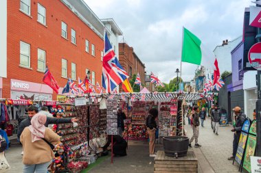 Londra, İngiltere - 29 Eylül 2024: canlı bir Camden market sahnesi bayrakları ve renkli tezgahlarla. Zıplayanlar canlı atmosferin keyfini çıkarırken hediyelik eşyalar ve yerel el sanatları araştırıyorlar..