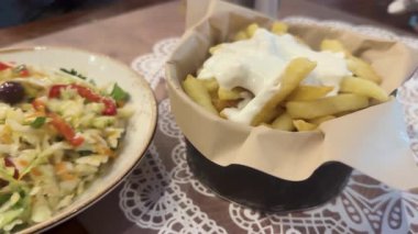 Sıcak bir yerel lokantada Poliki adında ferahlatıcı bir Yunan salatasının yanında kremalı sosla kaplı kızarmış patateslerin tadını çıkarın..