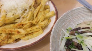 Peynirle kaplanmış kızarmış patateslerden servis edilen tavada pilav, soğanlı kızarmış mürekkep balığı ve yanında da limon dilimi olan karides..