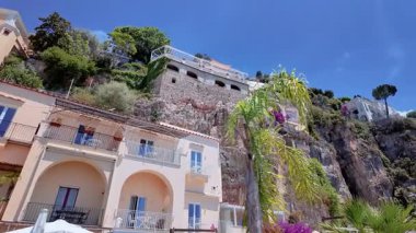 Positano, İtalya - 15 Haziran 2024: Ziyaretçiler canlı Positano rıhtımında geziniyor, renkli binalar, deniz manzaralı restoranlar ve Amalfi Sahili boyunca güneşli havanın keyfini çıkarıyorlar.