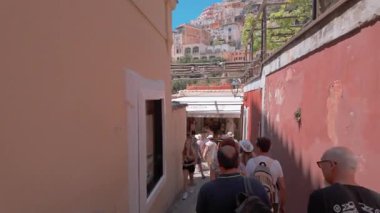 Positano, İtalya - 15 Haziran 2024: Ziyaretçiler Positano 'da dükkanlar ve canlı mimari ile çevrili pitoresk hareketli bir sokakta geziniyorlar. 