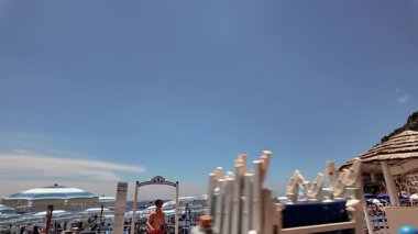 Positano, İtalya - 15 Haziran 2024: Amalfi Sahili 'ndeki sahil boyunca yürümek, parlak şemsiyeler ve resimli uçurum kenti ile çevrili.