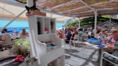 Positano, İtalya - 15 Haziran 2024: Amalfi Sahili 'ndeki sahil boyunca yürümek, parlak şemsiyeler ve resimli uçurum kenti ile çevrili. 