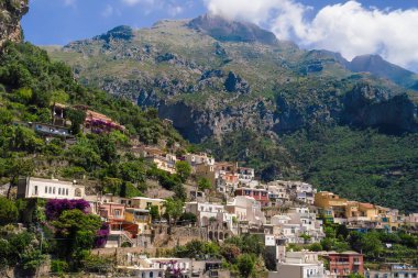 İtalya 'nın Amalfi Sahili' ndeki çarpıcı uçurum kenarındaki Positano köyünü keşfedin. Dramatik dağlara ve yemyeşil yeşilliklere yuva yapmış renkli binalar..