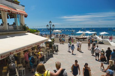 Positano, İtalya - 15 Haziran 2024: Ziyaretçiler güneşli bir gökyüzünün altında Amalfi Sahili 'nin berrak mavi sularında dinlenen Positano' nun manzaralı gezinti alanını keşfediyorlar..