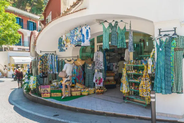 Positano, İtalya - 15 Haziran 2024: Amalfi Sahili 'ndeki turistler, sıcak yaz güneşinin altında canlı elbiseler ve güneş şapkalarıyla çevrili Positano' da renkli bir butiği keşfettiler.
