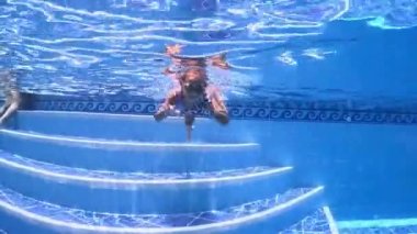 Küçük kızlar, kız kardeşler, üçüzler bir havuzda maske takıp suyun altında şnorkelle yüzerler. 3 yaşındaki yüksek kaliteli 4k 'lık üçlü kız kardeşler.