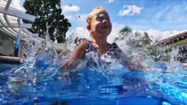 Küçük kız suyun altındaki havuza atlar. Yüksek kalite 4k görüntü