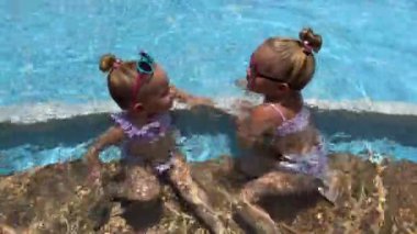 Üçüzler, 3-4 yaşlarındaki üç kız kardeş, havuzda oynuyorlar, güneş gözlüklü ikizler. Yüksek kalite 4k görüntü