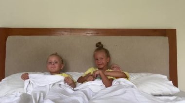 Üçüzler, 3-4 yaşlarındaki üç kız kardeş, pijamalarıyla yatakta oynuyorlar, ikizler. Zıplamak, oturmak, yalan söylemek, kitap okumak, oynamak