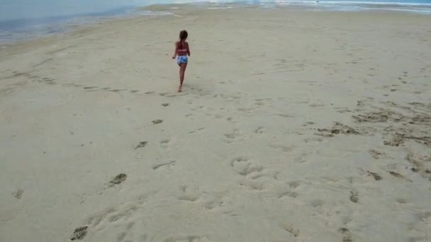 모래사장을 뛰어다니고 바다의 흔적을 남기는 수영복입고 달리는 고품질 — 비디오