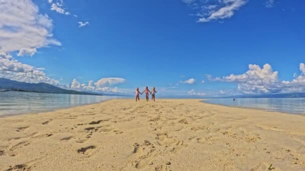 3人の小さな女の子4歳実行していると海 浅い水 澄んだ水 黄色の砂の中に唾を吐く砂の水着で遊んで 雲三連姉妹の子供たちはビーチで遊ぶと — ストック動画