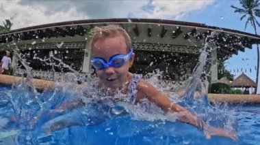Küçük bir kız havuza atlıyor, tamamen suyun altında küçük bir kız suya atlıyor. Yüksek kaliteli FullHD görüntüler