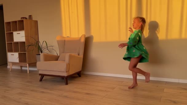Een Klein Meisje Een Groene Jurk Draait Blootsvoets Een Kamer — Stockvideo
