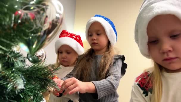 Τρεις Μικρές Αδελφές Τρίδυμα Διακοσμούν Χριστουγεννιάτικο Δέντρο Παιχνίδια Και Γιρλάντες — Αρχείο Βίντεο