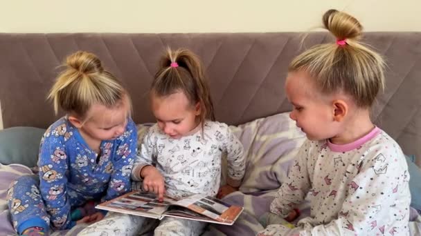 Små Systrar Trillingar Läser Bok Tillsammans Medan Sitter Sängen Har — Stockvideo