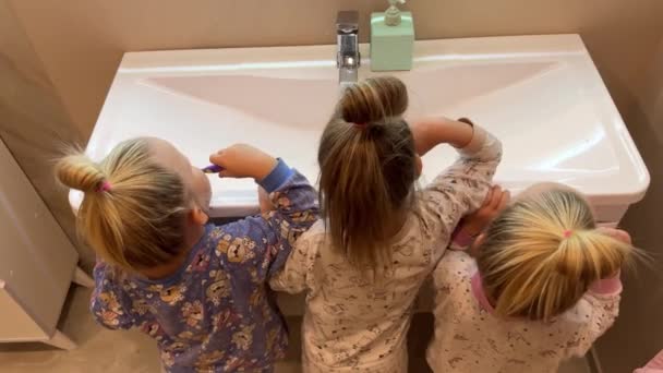 Kleine Schwestern Drillinge Zwillinge Zähne Putzen Badezimmer Vor Dem Spiegel — Stockvideo