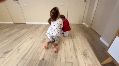 Üç küçük kız kardeş odada çıldırıyor, pijama giyiyorlar, oda büyük. Yüksek kalite 4k görüntü