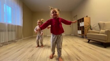 Üç küçük kız kardeş odada çıldırıyor, pijama giyiyorlar, oda büyük. Yüksek kalite 4k görüntü