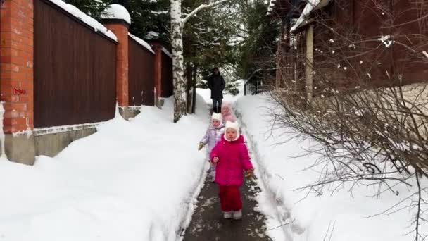 シスターズ トリプル 小さな女の子は 次々と冬の狭い道を歩き 父は後ろを歩いています 冬は雪が降っています 高品質の4K映像 — ストック動画