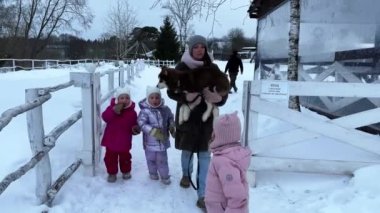 Anne ve üçüzlerin kızı kışın kahverengi köpek yavrusuyla yürüyor, anne kucağında köpek yavrusuyla. Yüksek kalite 4K görüntü. Yüksek kalite 4k görüntü