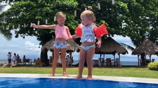 Zwillingsschwestern Badeanzügen Springen Einen Blauen Wasserpool Ufer Der Tropischen Insel — Stockvideo