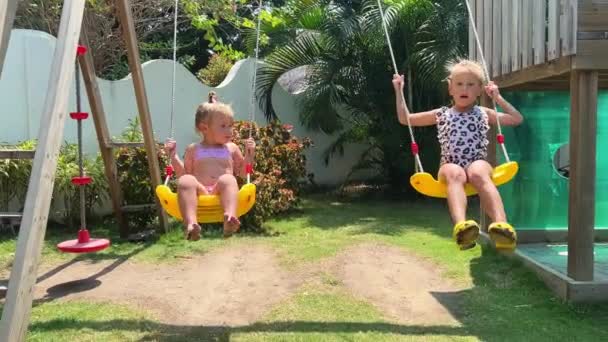 Zwei Schwestern Badeanzügen Auf Einer Schaukel Kleine Mädchen Badeanzügen Hinter — Stockvideo
