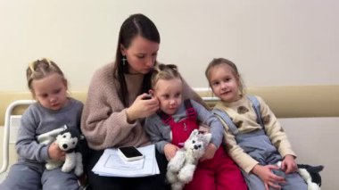 Anne ve küçük üçlü kızları klinikte bir doktor bekliyorlar. Yüksek kalite 4k görüntü