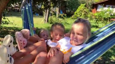 Triplet kardeşler yazın bahçede hamakta sallanıyorlar. Yüksek kalite 4k görüntü