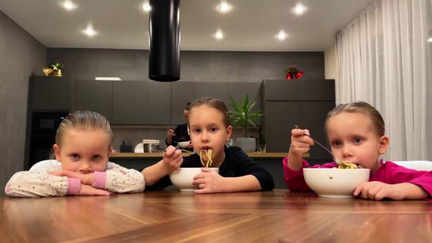 キッチンの自宅で白い皿からスパゲッティを食べる3人の小さな三人の姉妹 高品質の4K映像 — ストック動画