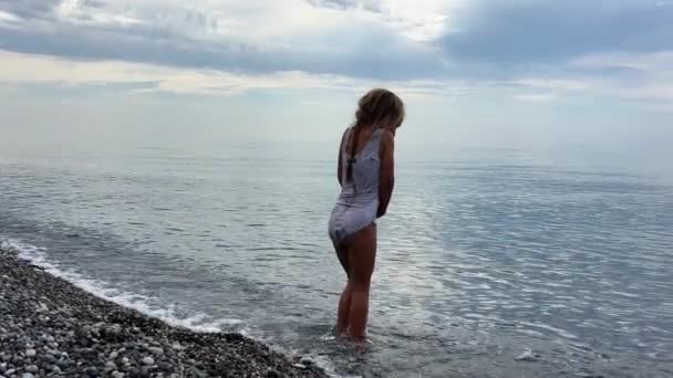 Kleines Mädchen Steht Kalten Wasser Des Meeres Einem Kieselstrand Der Lizenzfreies Stock-Filmmaterial