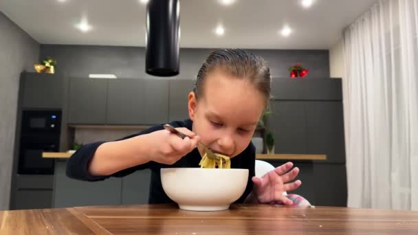 キッチンで白い皿からスパゲッティを食べる黒いセーターのベビーガール 高品質の4K映像 — ストック動画