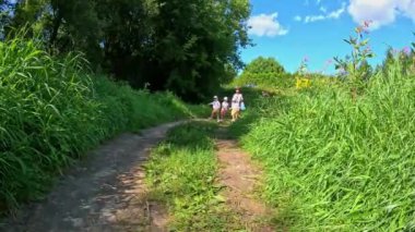 Üç küçük üçüz kız kardeş dizlerine kadar sıcak bir nehirde kırmızı can yelekleri giyip sörf gezisi için bekliyorlar. Yüksek kalite 4k görüntü