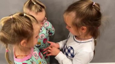 Kız, küçük kız kardeşlerine kayıp bebek dişini gösteriyor. Evde pijama giymişler bile. Yüksek kalite 4k görüntü