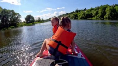 Bu neşeli video iki çocuğu gösteriyor, bir erkek ve bir kız, güneşli bir günün tadını çıkarıyorlar, kürek çekiyorlar ve birlikte oynuyorlar.