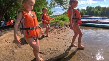 Küçük kızları olan bir aile yazın nehir boyunca özsuyunda yüzer, kıyıda ağaçlar yetişir, çocuklar can yeleği giyer. Yüksek kalite 4k görüntü