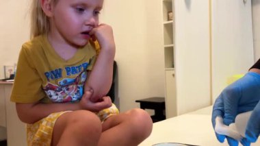 Küçük bir kız, bir tıp odasında dirsek yarası için tedavi görüyor. Yüksek kalite 4k görüntü