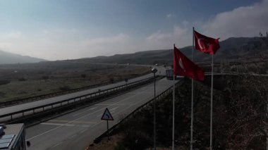 Türkiye 'de otoyol boyunca beyaz bir karavan sürüyor, İHA görüntüleri, kurumuş tarlalar ve kahverengi dağlar, güneş parlıyor. Yüksek kalite 4k görüntü