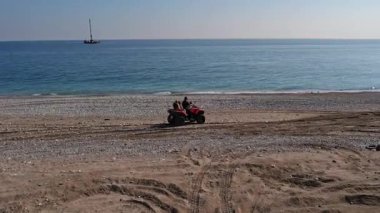 Anne ve üç küçük kızı deniz boyunca sahil boyunca bir dörtlü bisiklete biniyorlar. Yüksek kalite 4k görüntü