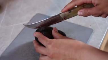 Bir kız, bir Türk bıçağıyla bir avokadoyu kemik sapıyla keser. Yüksek kalite 4k görüntü