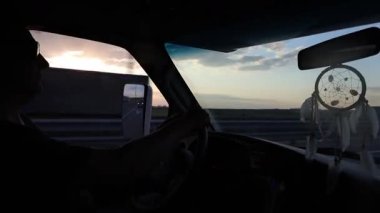 Bir adam gün batımında bir oyuk karavanı kullanıyor, bir düş kapanı aynada asılı. Yüksek kalite 4k görüntü