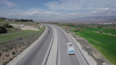Bir karavanda seyahat eden bir karavan, ilkbaharda bir dron tarafından vurulan tarlalar ve dağlar arasında yol boyunca yolculuk ediyor. Yüksek kalite 4k görüntü